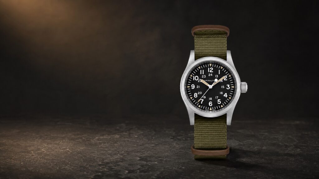 Hamilton Khaki Field Mechanical H69439931 with a black dial and olive textile strap in a dark studio setting.