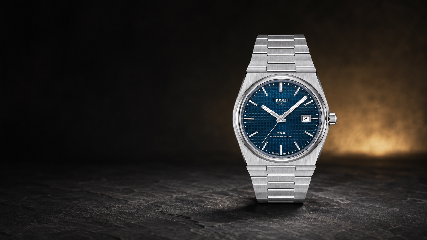 Blue-dial Tissot PRX Powermatic 80 T137.407.11.041.00 on its integrated steel bracelet in a dark studio setting.