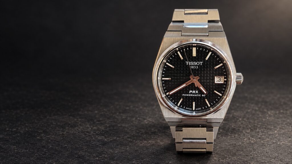 AI-composed illustration based on a photograph of a black-dial Tissot PRX 35mm Powermatic 80, against dark stone.
